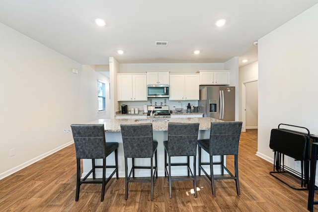 kitchen with white cabinets, stainless steel appliances, and hardwood / wood-style floors