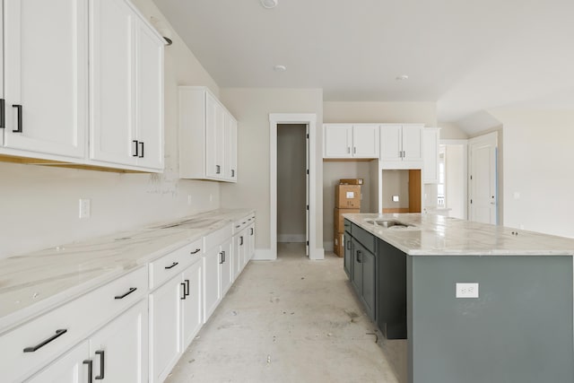 kitchen featuring white cabinets, light stone countertops, and a center island