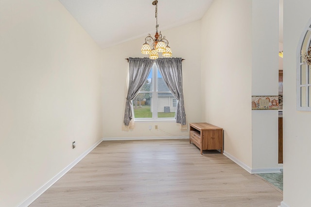 unfurnished dining area featuring a chandelier, light wood-type flooring, lofted ceiling, and baseboards