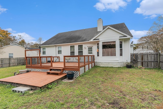 back of property with a chimney, a shingled roof, a lawn, a deck, and a fenced backyard