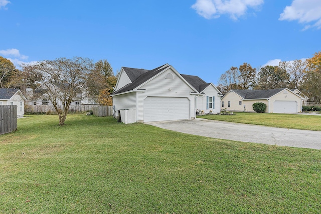 view of side of home with a lawn, an attached garage, fence, a residential view, and driveway