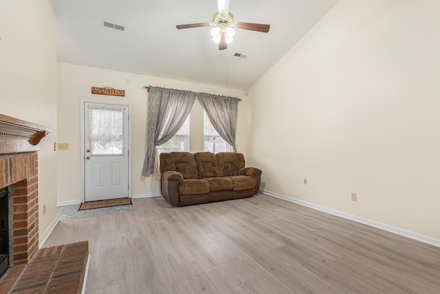 unfurnished living room featuring light wood-type flooring, a brick fireplace, visible vents, and lofted ceiling