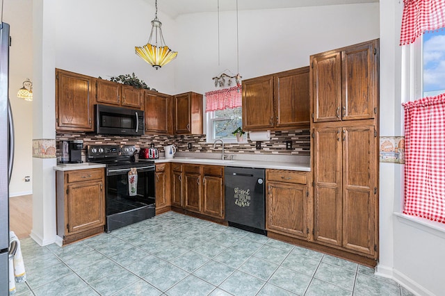 kitchen with light countertops, hanging light fixtures, decorative backsplash, a sink, and black appliances