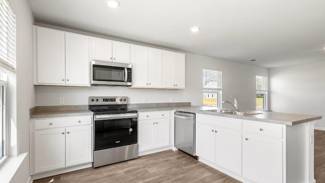 1009 Folly Rd, Summerton, SC 29148 - kitchen with a peninsula, light wood-type flooring, white cabinetry, a sink, and stainless steel appliances