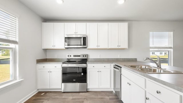 1009 Folly Rd, Summerton, SC 29148 - kitchen featuring light countertops, white cabinetry, appliances with stainless steel finishes, a sink, and wood finished floors