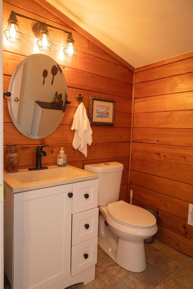 bathroom featuring toilet, lofted ceiling, vanity, and wooden walls