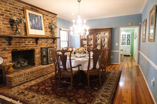 dining space featuring ornamental molding, hardwood / wood-style floors, a brick fireplace, and a notable chandelier