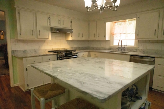 kitchen with sink, appliances with stainless steel finishes, backsplash, light stone counters, and a kitchen island