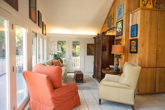 living area featuring french doors, light tile patterned flooring, high vaulted ceiling, and wood walls