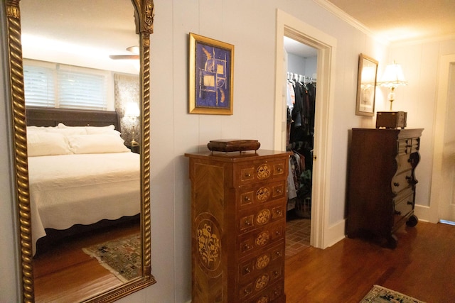 bedroom with a closet, crown molding, a walk in closet, and dark hardwood / wood-style floors