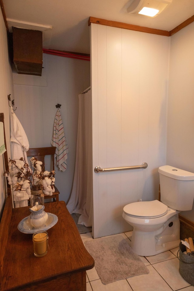 bathroom with tile patterned flooring, crown molding, and toilet