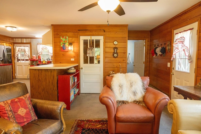 living room featuring ceiling fan, wooden walls, and carpet flooring