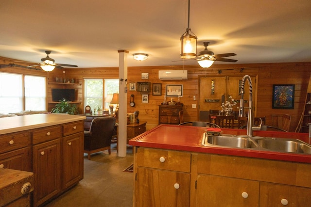 kitchen with a wall mounted air conditioner, wooden walls, sink, and hanging light fixtures