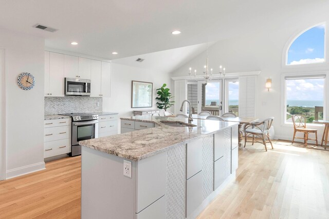 kitchen with stainless steel appliances, vaulted ceiling, sink, light hardwood / wood-style flooring, and white cabinets