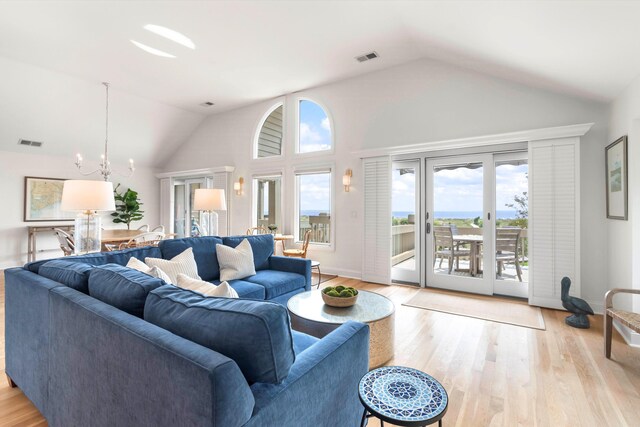 living room with a chandelier, vaulted ceiling, and light hardwood / wood-style flooring