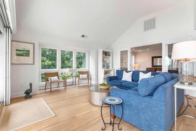 living room featuring light wood-type flooring and high vaulted ceiling