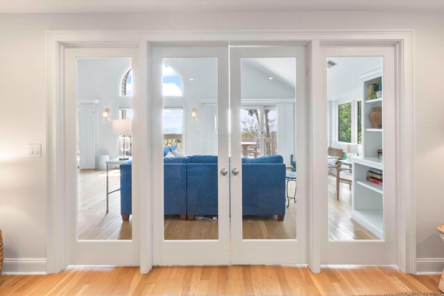 living room featuring plenty of natural light, light hardwood / wood-style floors, and vaulted ceiling