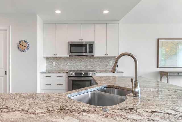 kitchen featuring white cabinets, light stone counters, sink, and high quality fridge