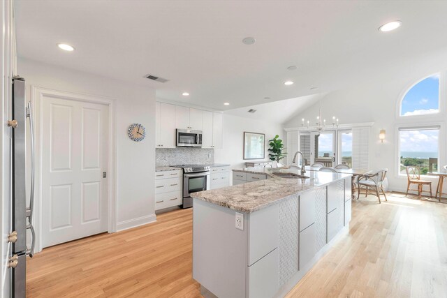 kitchen with a large island with sink, sink, white cabinets, and appliances with stainless steel finishes