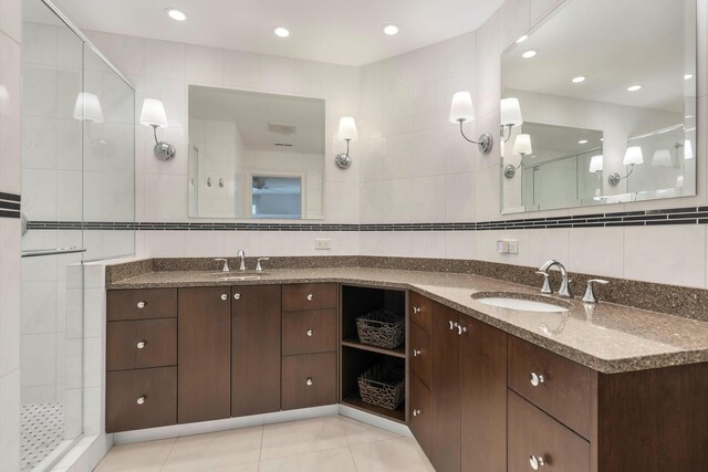 bathroom with vanity, a shower with shower door, tile walls, and tasteful backsplash