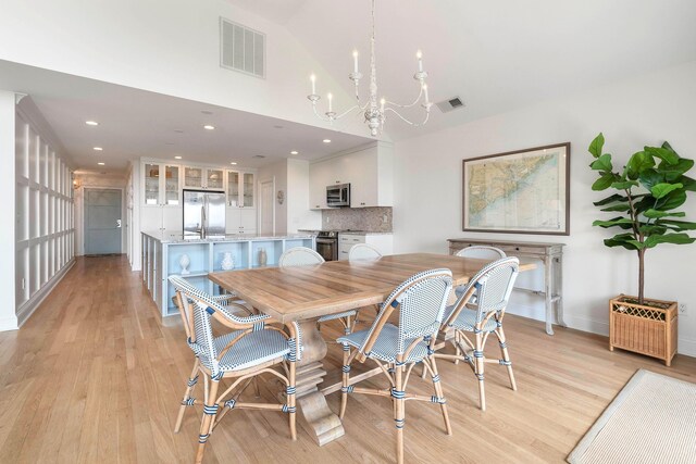 dining area with light hardwood / wood-style floors and a notable chandelier