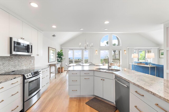 kitchen featuring sink, stainless steel appliances, light hardwood / wood-style flooring, vaulted ceiling, and white cabinets