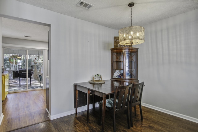 dining area featuring baseboards, wood finished floors, visible vents, and a notable chandelier