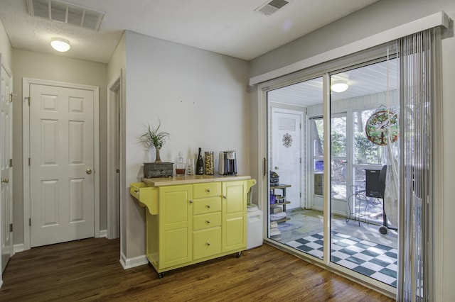 doorway to outside with a textured ceiling, visible vents, and dark wood-type flooring