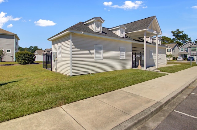 view of side of property featuring a shingled roof and a yard