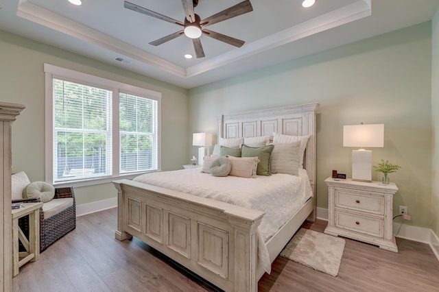 bedroom featuring ceiling fan, a raised ceiling, and multiple windows