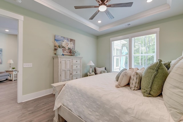 bedroom featuring ceiling fan, a raised ceiling, and light hardwood / wood-style floors