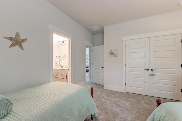 bedroom featuring light colored carpet, ensuite bath, and a closet