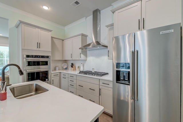 kitchen with sink, crown molding, stainless steel appliances, decorative backsplash, and wall chimney range hood