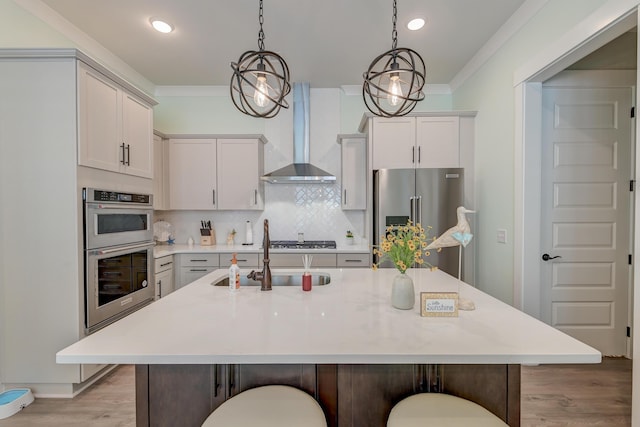 kitchen with appliances with stainless steel finishes, backsplash, a kitchen breakfast bar, a center island with sink, and wall chimney exhaust hood