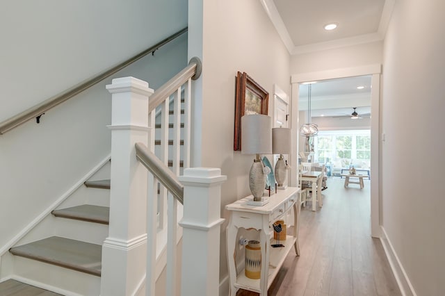 stairway featuring hardwood / wood-style flooring, ceiling fan, and ornamental molding