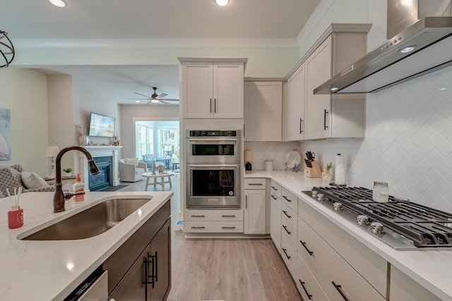 kitchen with sink, decorative backsplash, wall chimney range hood, and stainless steel appliances