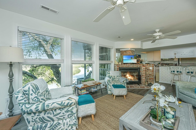 living room featuring a fireplace, hardwood / wood-style floors, and ceiling fan