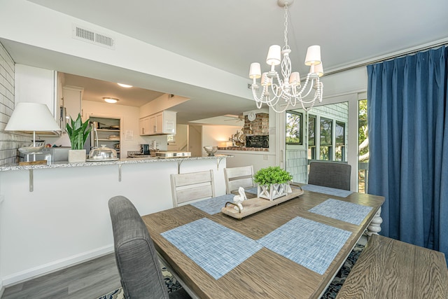 dining space featuring brick wall, a notable chandelier, and hardwood / wood-style flooring