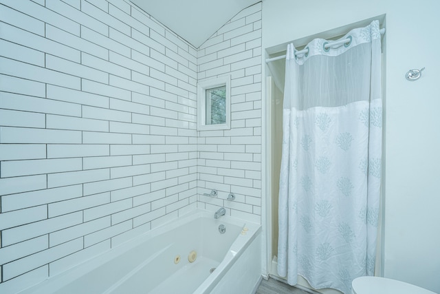 bathroom featuring lofted ceiling, shower / bath combination with curtain, and toilet