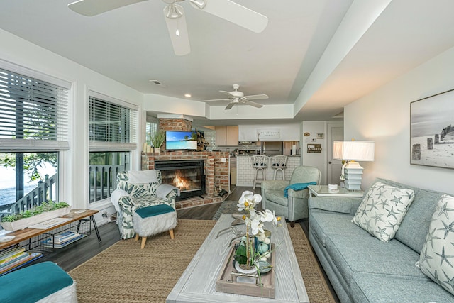 living room featuring wood-type flooring, ceiling fan, and a fireplace