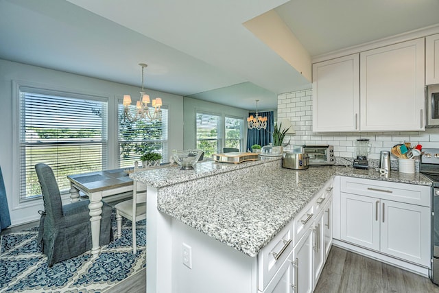 kitchen featuring backsplash, light hardwood / wood-style floors, an inviting chandelier, and white cabinetry