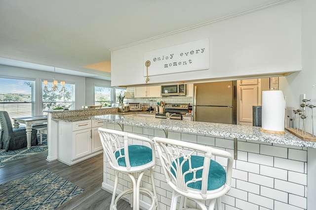 kitchen featuring appliances with stainless steel finishes, light stone counters, dark hardwood / wood-style flooring, and hanging light fixtures