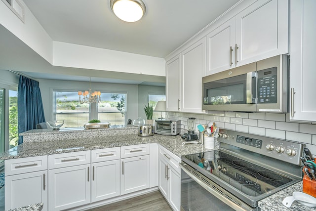 kitchen with white cabinets, backsplash, stainless steel appliances, a notable chandelier, and light hardwood / wood-style floors