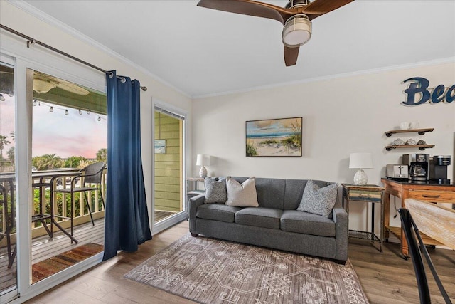 living room featuring wood-type flooring, ornamental molding, and ceiling fan