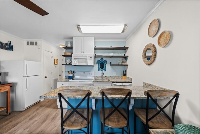 kitchen featuring a kitchen breakfast bar, white cabinets, white appliances, light wood-type flooring, and crown molding