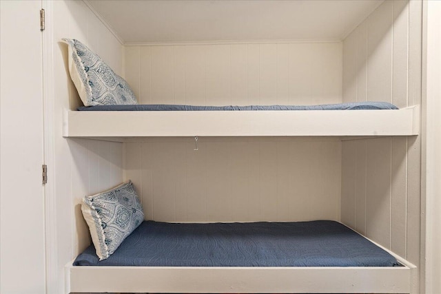 bedroom with ornamental molding and wood walls