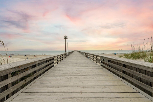 view of dock featuring a water view and a beach view