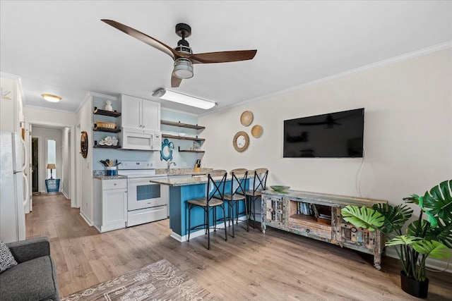 kitchen featuring light wood-type flooring, white appliances, white cabinetry, and a breakfast bar area