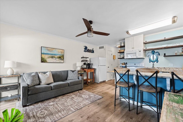 living room featuring light wood-type flooring, ceiling fan, and crown molding