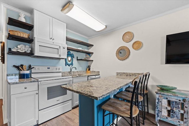 kitchen featuring white appliances, light hardwood / wood-style floors, white cabinetry, and a breakfast bar area